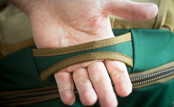 A person sliding their hand into the top grab handle of the Guide's Edition Synik 22.